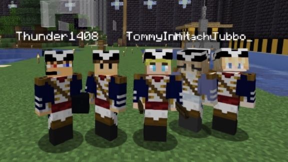 This is a screenshot from Wilbur's Minecraft stream. It shows several L'manbergians in a line smiling at the camera. From left to right it's Jack, Wilbur, Tommy, Niki, and Tubbo. They all wear their L'manberg uniforms. The van and the L'manberg walls are seen in the background.